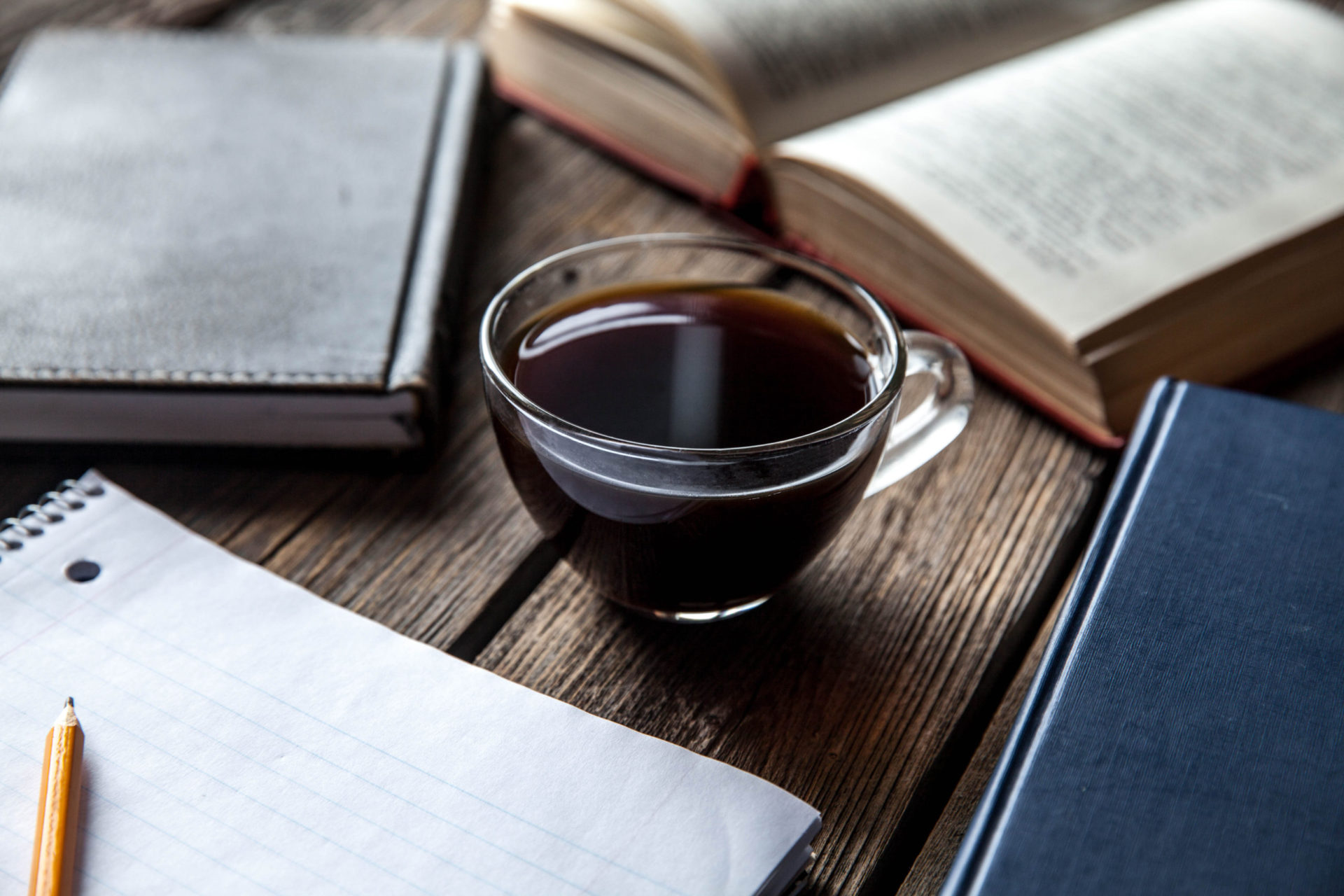 black book and a cup of coffee on a wooden background