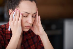 Woman with a headache rubbing forehead.