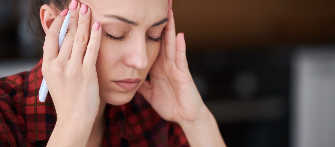 Woman with a headache rubbing forehead.